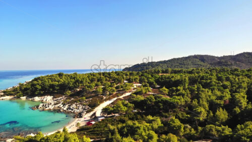Video - Aerial drone view of the Aegean sea rocky coast with blue transparent water, multiple greenery, hills. Greece