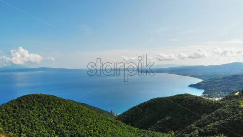 Video - Aerial drone view of the Aegean sea coast in Greece. Hills covered with greenery, land and sea in the distance