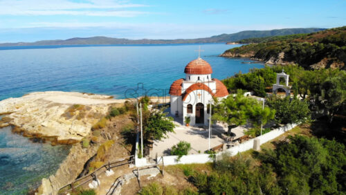Video - Aerial drone view of the Nea Roda church situated on the Aegean sea coast, Greece. Land on the background