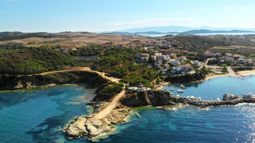 Video - Aerial drone view of the Nea Roda situated on the Aegean sea coast, Greece. Multiple buildings with greenery, church near the shore