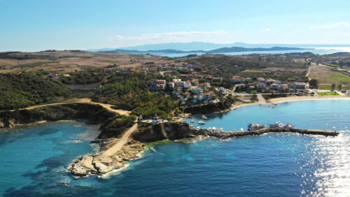 Video - Aerial drone view of the Nea Roda situated on the Aegean sea coast, Greece. Multiple buildings with greenery, church near the shore