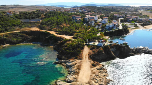 Video - Aerial drone view of the Nea Roda situated on the Aegean sea coast, Greece. Multiple buildings with greenery, church near the shore