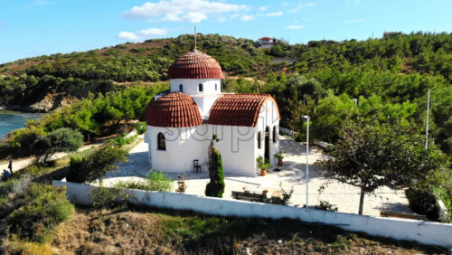 Video - Aerial drone view of the Nea Roda church situated on the Aegean sea coast, Greece. Green hill on the background