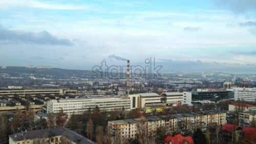 Video - Aerial drone view of Chisinau. Thermal station with smoke coming out of the tube. Buildings, roads and bare trees. Cloudy weather. Moldova