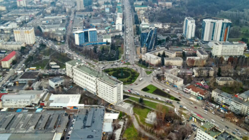Video - Aerial drone view of Chisinau. Panorama view of multiple buildings, roads with moving cars and bare trees. Cloudy weather. Moldova