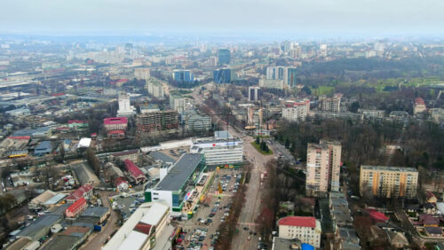 Video - Aerial drone view of Chisinau, hyperlapse. Panorama view of multiple buildings, roads and parkings with moving cars and bare trees. Cloudy weather. Moldova