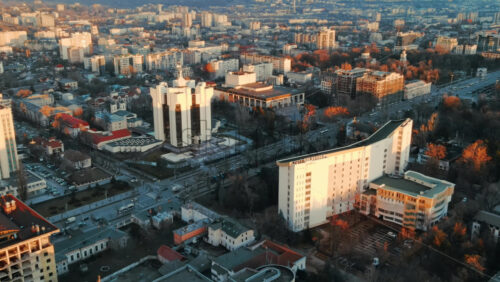 Video - Aerial drone view of Chisinau at sunset. Panorama view of the Presidency and Parliament, multiple buildings in city center, roads with moving cars, bare trees. Moldova