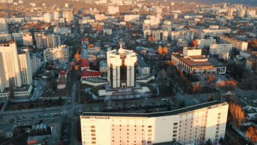 Video - Aerial drone view of Chisinau at sunset. Panorama view of the Presidency and Parliament, multiple buildings in city center, roads with moving cars, bare trees. Moldova