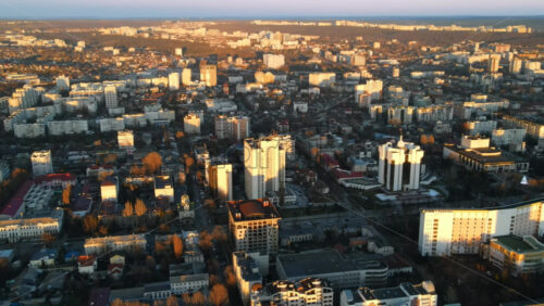 Video - Aerial drone view of Chisinau at sunset. Panorama view of the Presidency and Parliament, multiple buildings in city center, roads with moving cars, bare trees. Moldova