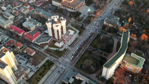 Video - Aerial drone view of Chisinau at sunset. View of the Presidency and Parliament, multiple buildings in city center, roads with moving cars, bare trees. Moldova