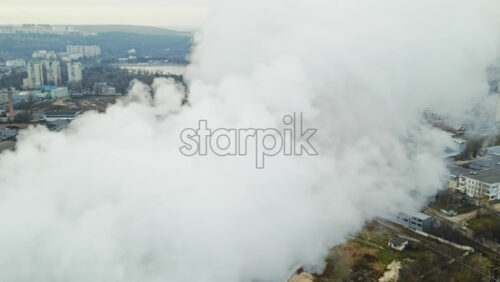 Video - Aerial drone view of thermal station with smoke coming out of the tube. Buildings, roads and bare trees on the background. Cloudy weather. Chisinau, Moldova