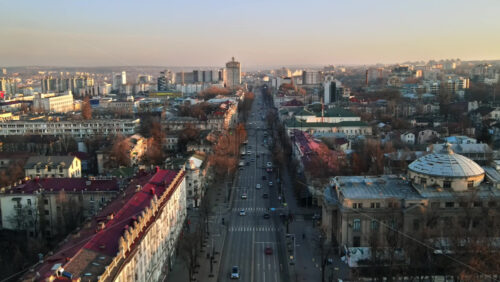 Video - Aerial drone view of Chisinau downtown. Panorama view of a street with multiple buildings, road with moving cars and bare trees. Moldova