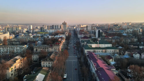 Video - Aerial drone view of Chisinau downtown. Panorama view of a street with multiple buildings, road with moving cars and bare trees. Moldova