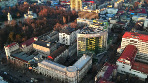 Video - CHISINAU, MOLDOVA - JANUARY 1, 2021: Aerial drone panorama view of multiple buildings, road with moving cars, central park with bare trees