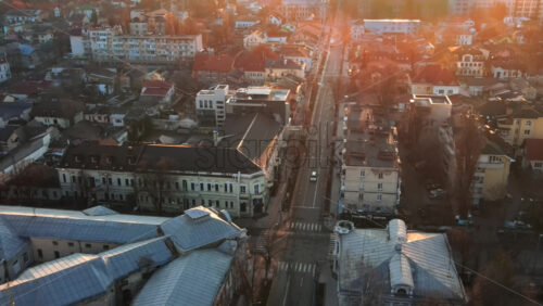 Video - CHISINAU, MOLDOVA - JANUARY 1, 2021: Aerial drone view of the city at sunset. Panorama view of multiple buildings, roads with moving cars, bare trees