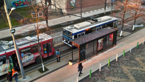 Video - CHISINAU, MOLDOVA - JANUARY 1, 2021: Aerial drone view of a bus stop with buses, walking people, bare trees
