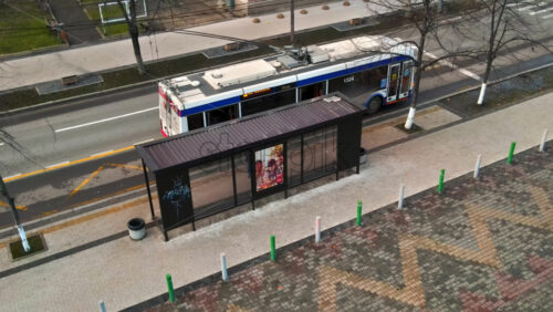 Video - CHISINAU, MOLDOVA - JANUARY 1, 2021: Aerial drone view of a bus stop with a man getting out, bare trees, building on the background