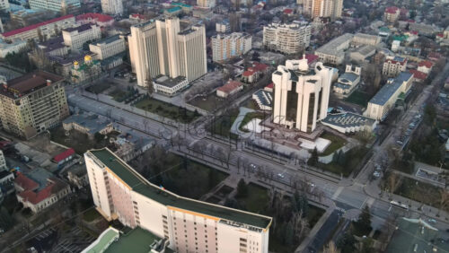 Video - Aerial drone view of Chisinau. Panorama view of the Presidency and Parliament, multiple buildings in city center, roads with moving cars, bare trees. Moldova