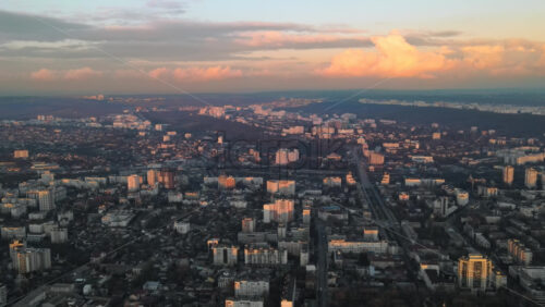 Video - Aerial drone view of Chisinau at sunset. Panorama view of multiple buildings, roads with moving cars, bare trees. Moldova