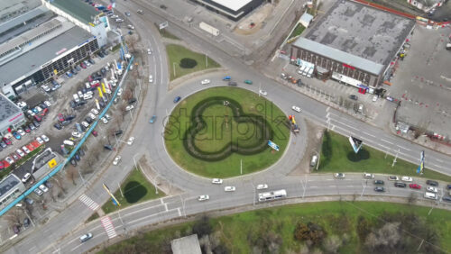 Video - CHISINAU, MOLDOVA - JANUARY 1, 2021: Aerial drone view of a road with roundabout intersection and multiple moving cars, parking, store and bare trees