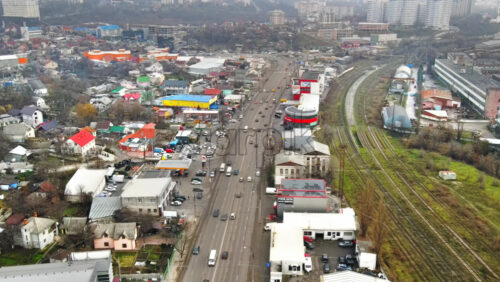 Video - CHISINAU, MOLDOVA - JANUARY 1, 2021: Aerial drone panorama view of a road with moving cars, residential and commercial buildings, railway and bare trees