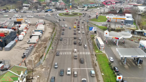 Video - CHISINAU, MOLDOVA - JANUARY 1, 2021: Aerial drone view of Chisinau. Road with roundabout intersection and multiple moving cars, residential and commerical buildings, bare trees. Moldova