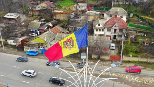 Video - CHISINAU, MOLDOVA - JANUARY 1, 2021: Aerial drone view of the Moldavian flag located on the roundabout intersection and multiple moving cars, residential buildings on the background