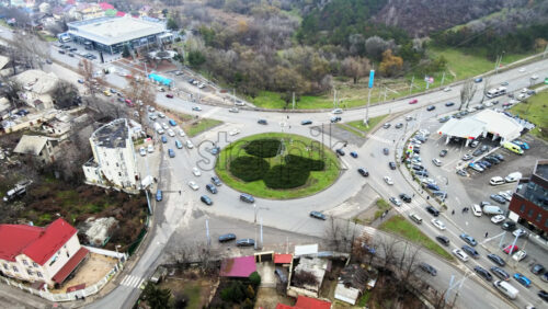 Video - CHISINAU, MOLDOVA - JANUARY 1, 2021: Aerial drone view of a road with roundabout intersection and multiple moving cars, residential buildings, parking and bare trees