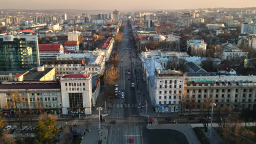 Video - CHISINAU, MOLDOVA - JANUARY 1, 2021: Aerial drone panorama view of downtown, street with multiple buildings, road with moving cars and bare trees