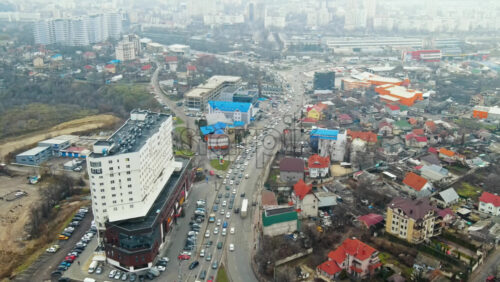 Video - CHISINAU, MOLDOVA - JANUARY 1, 2021: Aerial drone view of a road with multiple moving cars, residential and commercial buildings, bare trees