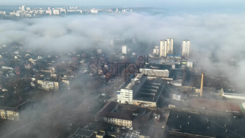 Video - Aerial drone view of Chisinau through the clouds. Panorama view of multiple buildings, roads with moving cars and bare trees. Moldova