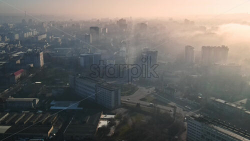 Video - Aerial drone view of Chisinau. Panorama view of multiple buildings, roads with moving cars and bare trees. Good weather with fog in the air. Moldova