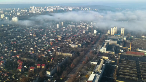 Video - Aerial drone view of Chisinau. Panorama view of multiple buildings, roads with moving cars and bare trees. Good weather with fog in the air and low clouds. Moldova