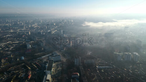 Video - Aerial drone view of Chisinau. Panorama view of multiple buildings, roads with moving cars and bare trees. Good weather with fog in the air and low clouds. Moldova