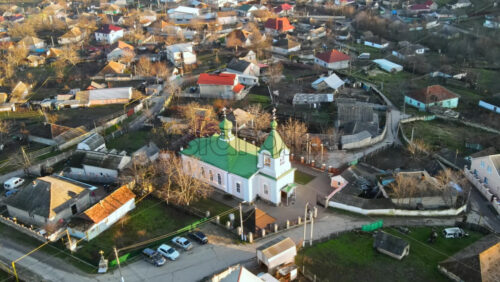 Video - Aerial drone view of a village. View of multiple residential buildings, country roads, bare trees and a church. Sunny weather. Moldova