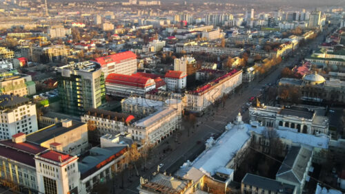 Video - CHISINAU, MOLDOVA - JANUARY 1, 2021: Aerial drone panorama view of downtown, street with multiple buildings, road with moving cars and bare trees