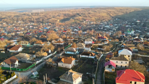 Video - Aerial drone view of a village. View of multiple residential buildings, country roads, bare trees. Sunny weather. Moldova