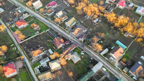 Video - Aerial drone view of a village. View of multiple residential buildings, country road with moving car, bare trees. Sunny weather. Moldova
