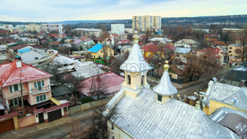 Video - Aerial drone view of a church in Chisinau, Moldova. Multiple buildings, road, church, Cloudy weather, bare trees, winter