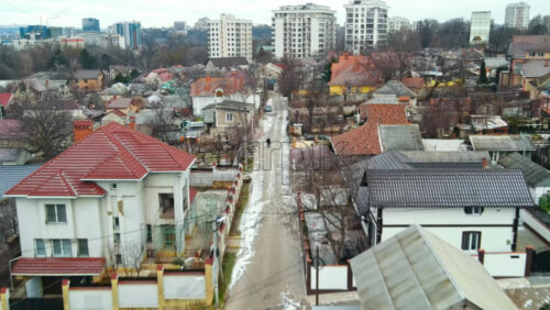 Video - Aerial drone view of a residential distict in Chisinau, Moldova. Multiple buildings, road, walking man, Cloudy weather, bare trees, winter