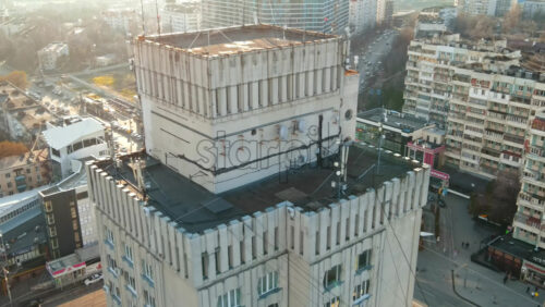 Video - CHISINAU, MOLDOVA - JANUARY 15, 2021: Aerial drone view of city at sunset. Residential building, stores, road with roundabout and moving cars. Bare trees, winter