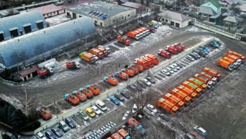 Video - Aerial drone view of industrial zone in Chisinau, Moldova. Multiple parked garbage trucks, hangars, Cloudy weather, bare trees, winter