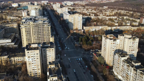 Video - CHISINAU, MOLDOVA - JANUARY 15, 2021: Aerial drone view of city at sunset. Multiple residential buildings, road with moving cars. Bare trees, winter