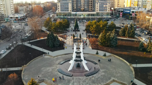 Video - CHISINAU, MOLDOVA - JANUARY 15, 2021: Aerial drone view of a Afghan memorial park in Chisinau, Moldova. Walking people, roads with cars, memorial, trees and buildings. Winter