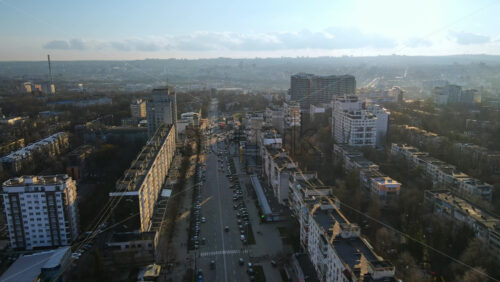 Video - CHISINAU, MOLDOVA - JANUARY 15, 2021: Aerial drone view of city at sunset. Multiple residential buildings, road with moving cars. Bare trees, winter