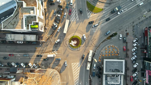 Video - CHISINAU, MOLDOVA - JANUARY 15, 2021: Aerial drone view of city at sunset. Stores, road with roundabout and moving cars. Bare trees, winter