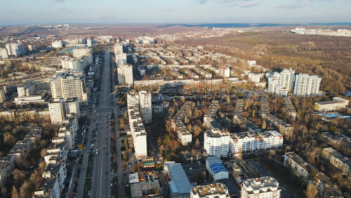 Video - Aerial drone view of Chisinau, Moldova at sunset. Multiple residential buildings, road with moving cars, fields on the background. Bare trees, winter