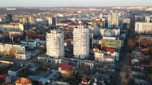 Video - Aerial drone view of Chisinau at sunset. Panorama view of multiple buildings, road with moving car, bare trees. Moldova