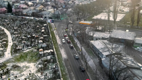 Video - Aerial drone view of a residential distict in Chisinau, Moldova. Multiple buildings, road, cemetery on the left, Cloudy weather, bare trees, winter