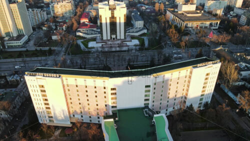 Video - Aerial drone view of Chisinau at sunset. Panorama view of the Presidency and Parliament, multiple buildings in city center, roads with moving cars, bare trees. Moldova